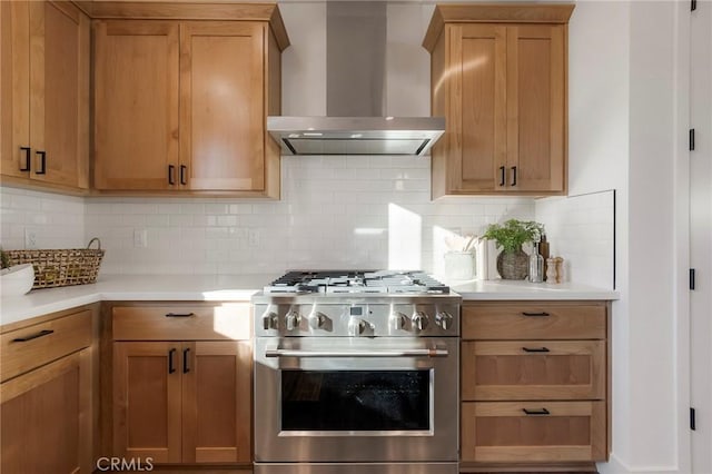 kitchen featuring high end stainless steel range oven, wall chimney exhaust hood, and decorative backsplash