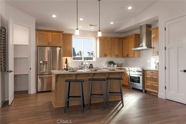 kitchen featuring hanging light fixtures, backsplash, high quality appliances, a kitchen island, and wall chimney exhaust hood