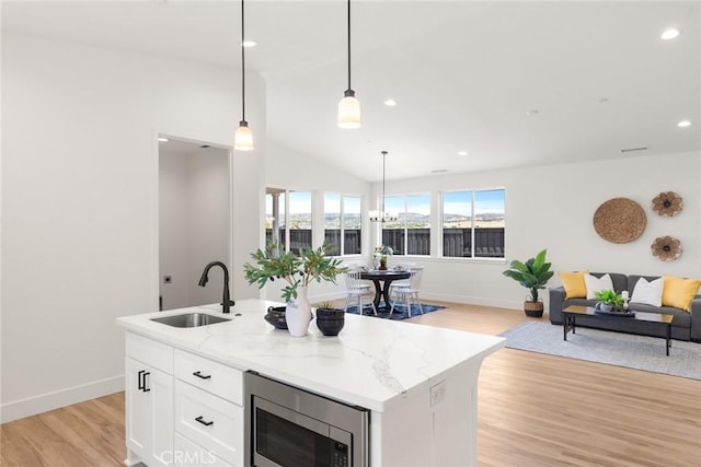 9 Harkness Ct, Chico, CA 95973 - kitchen featuring stainless steel microwave, open floor plan, light wood-style flooring, white cabinetry, and vaulted ceiling