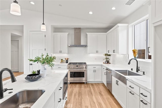 9 Harkness Ct, Chico, CA 95973 - kitchen with wall chimney range hood, appliances with stainless steel finishes, backsplash, white cabinets, and hanging light fixtures