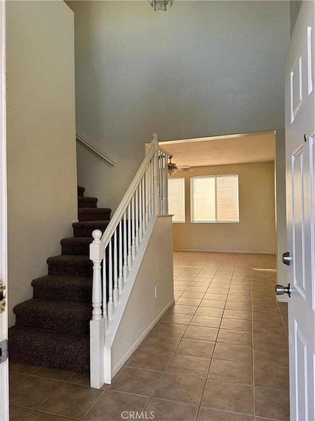 stairway featuring ceiling fan, tile patterned flooring, and a towering ceiling