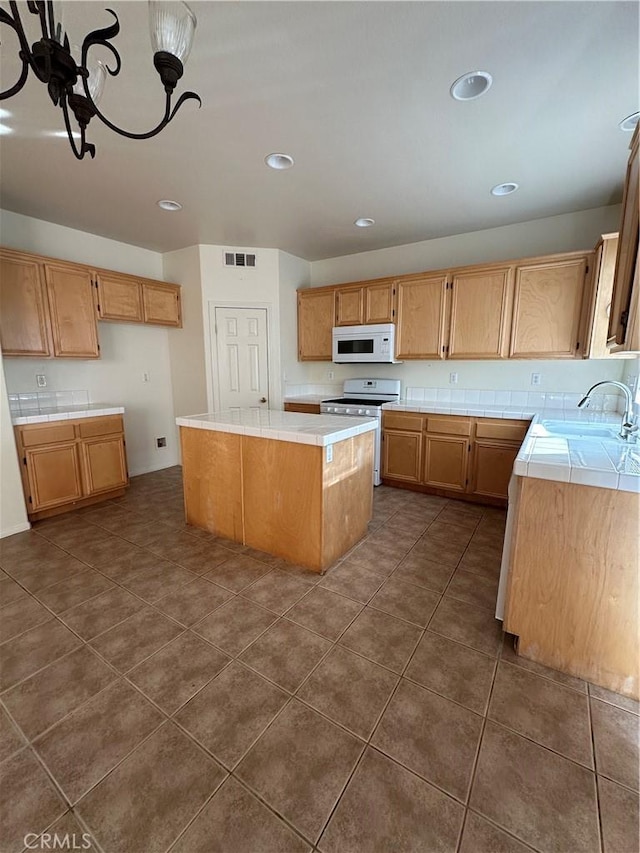 kitchen featuring white appliances, dark tile patterned flooring, sink, and a kitchen island