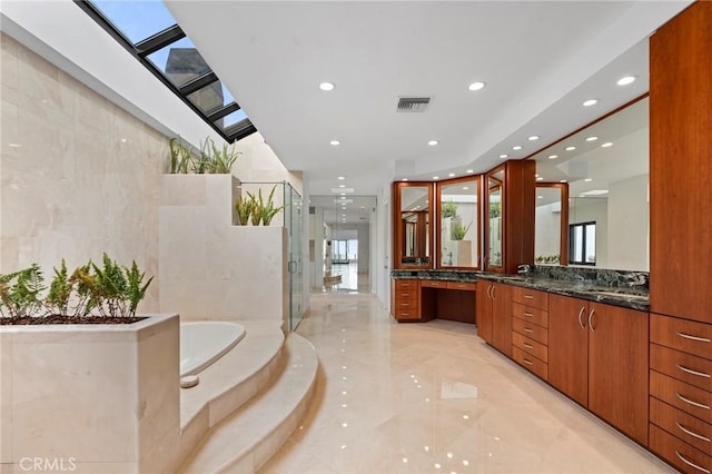 bathroom with vanity, a skylight, plus walk in shower, and tile walls