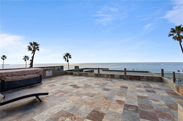 view of patio featuring a water view, an outdoor kitchen, and a hot tub