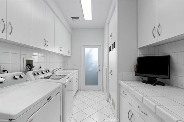 laundry area with cabinets, washer and clothes dryer, sink, and light tile patterned floors