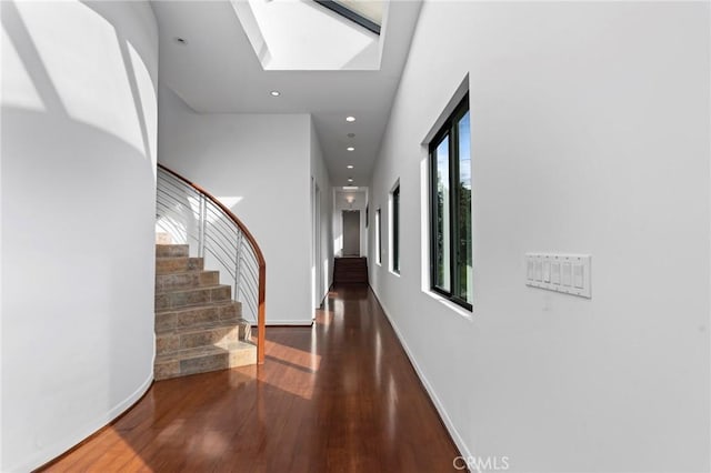 hall with a skylight and dark wood-type flooring