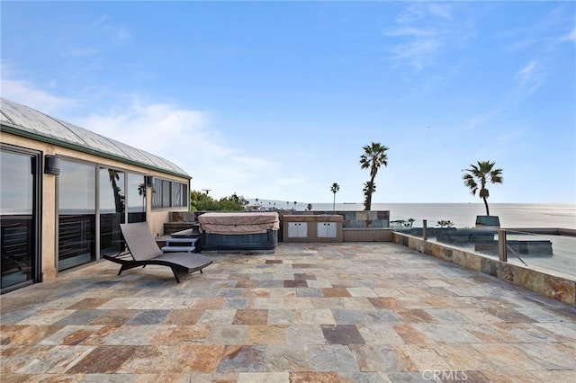 view of patio featuring a hot tub and a water view