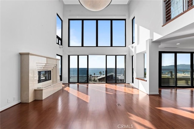 unfurnished living room with a wealth of natural light, a water and mountain view, and wood-type flooring