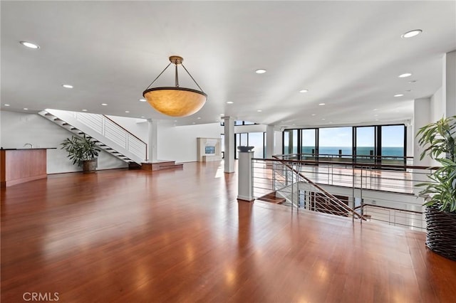 interior space with expansive windows, a water view, hardwood / wood-style floors, and ornate columns