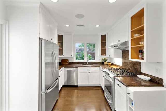 kitchen with dark wood-type flooring, sink, dark stone countertops, appliances with stainless steel finishes, and white cabinets