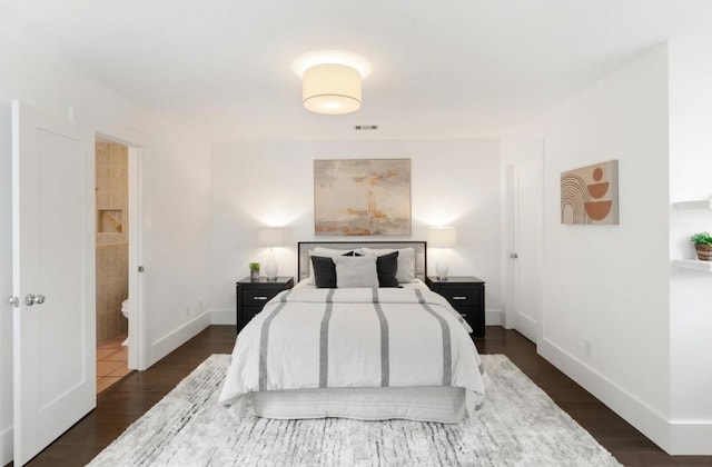 bedroom featuring connected bathroom and dark hardwood / wood-style flooring