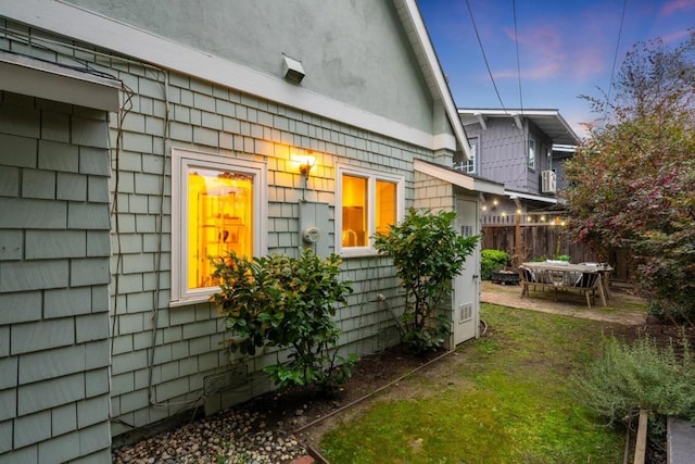 property exterior at dusk featuring a patio and a lawn