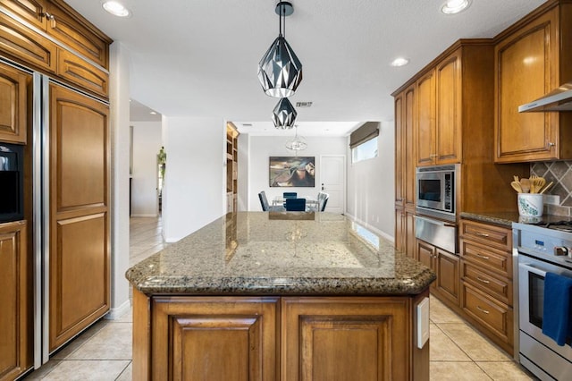 kitchen with pendant lighting, stainless steel microwave, range, and a kitchen island