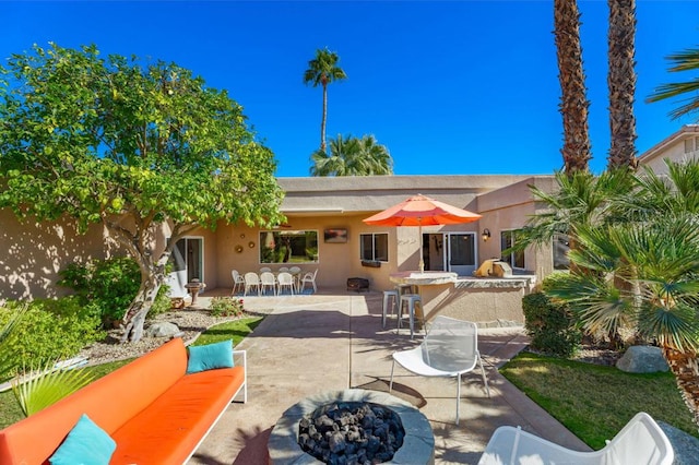 rear view of property featuring exterior bar, a patio area, and an outdoor living space with a fire pit