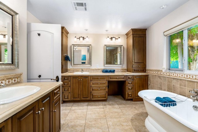 bathroom with a washtub, vanity, tile patterned floors, and tile walls