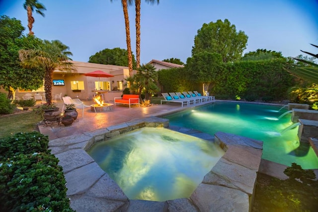 pool at dusk with an in ground hot tub, a patio, and an outdoor fire pit