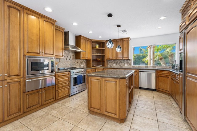 kitchen with wall chimney exhaust hood, a center island, dark stone countertops, pendant lighting, and stainless steel appliances