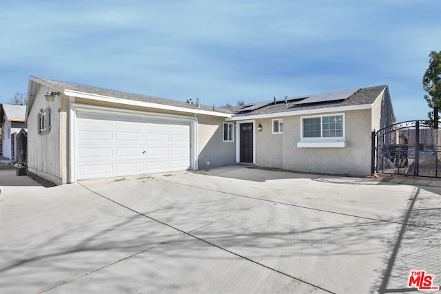 ranch-style home featuring a garage and solar panels