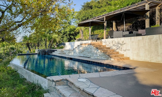 view of swimming pool featuring pool water feature and a patio area