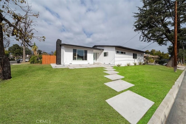 view of front facade featuring a chimney, fence, a front lawn, and a patio