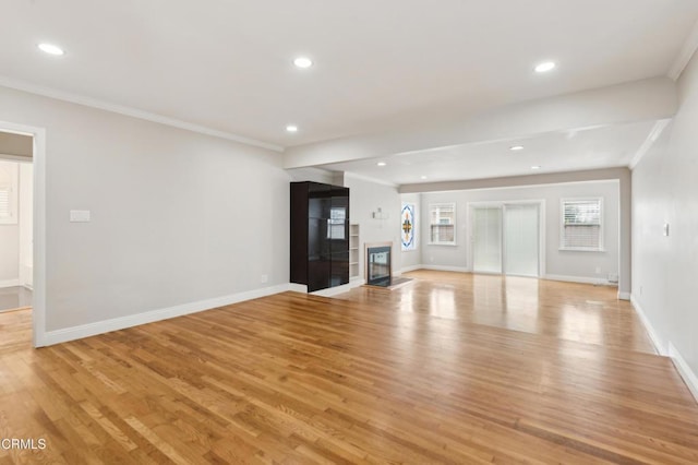 unfurnished living room featuring crown molding and light hardwood / wood-style flooring