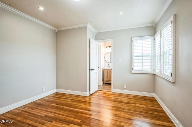 unfurnished bedroom with hardwood / wood-style flooring, crown molding, and connected bathroom