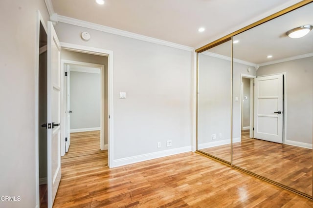 unfurnished bedroom featuring hardwood / wood-style flooring, ornamental molding, and a closet