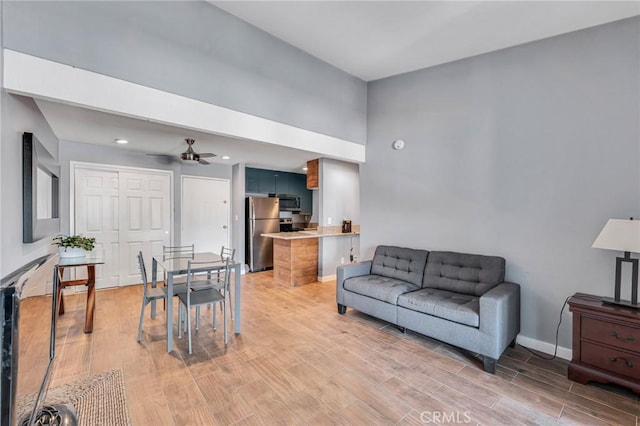 living area featuring a ceiling fan, baseboards, and wood finished floors