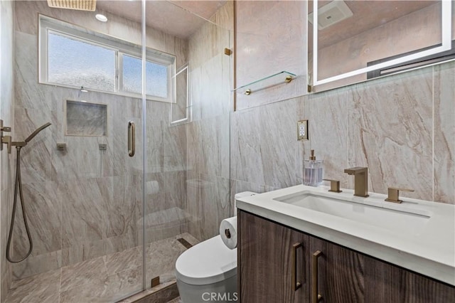 bathroom with vanity, toilet, a shower with shower door, and tile walls