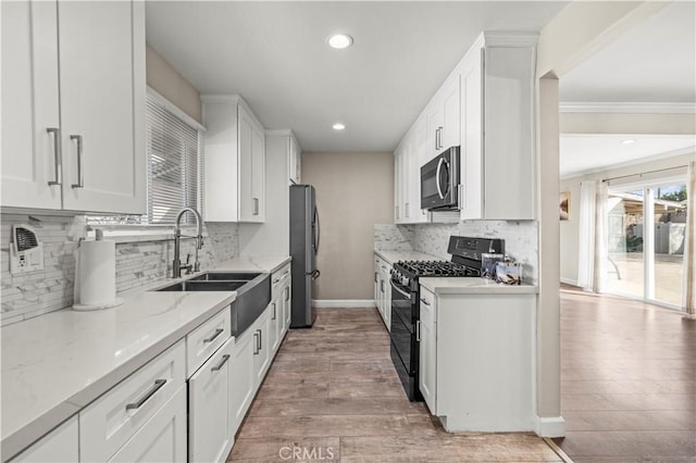 kitchen with white cabinetry, appliances with stainless steel finishes, light stone countertops, and sink