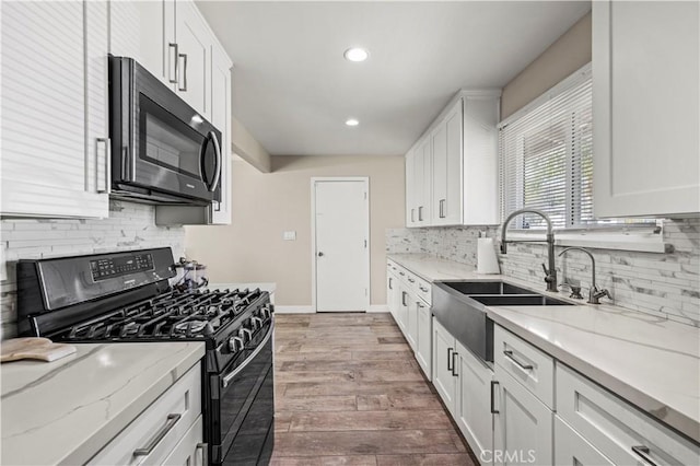 kitchen with gas range, light stone countertops, and white cabinets