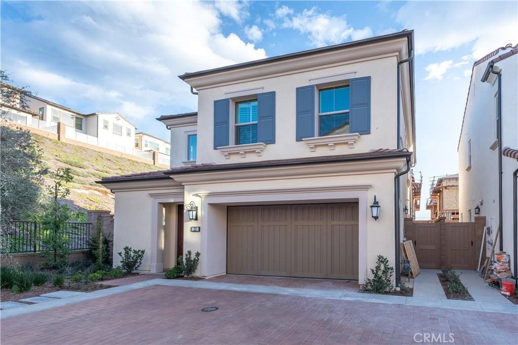 view of front of home with a garage, fence, decorative driveway, and stucco siding