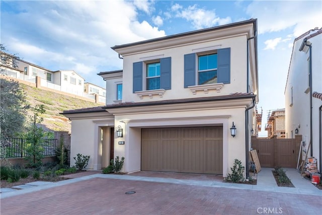 view of front of home with a garage, fence, decorative driveway, and stucco siding