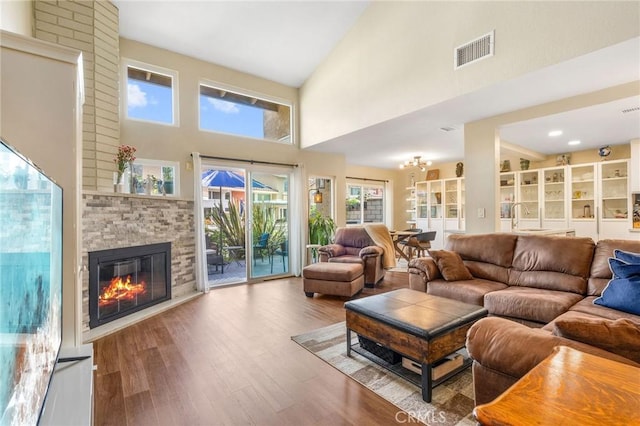 living room with sink, a stone fireplace, hardwood / wood-style floors, and high vaulted ceiling