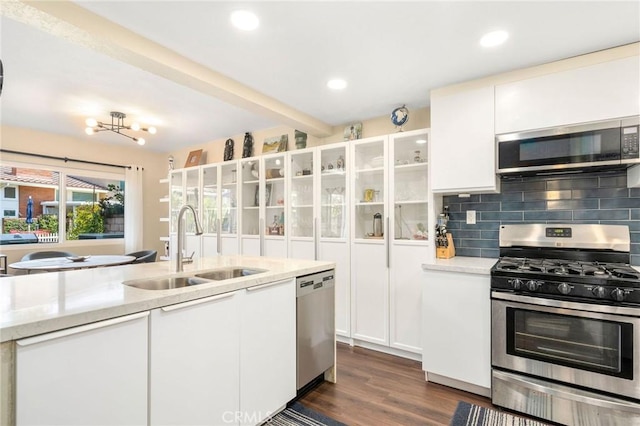 kitchen with sink, white cabinetry, stainless steel appliances, decorative backsplash, and beamed ceiling