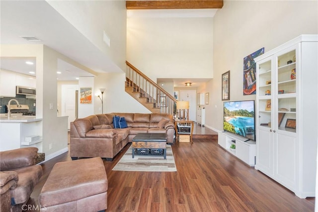 living room with a high ceiling, dark wood-type flooring, and beam ceiling