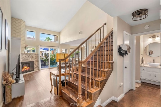 staircase with hardwood / wood-style floors, high vaulted ceiling, and sink