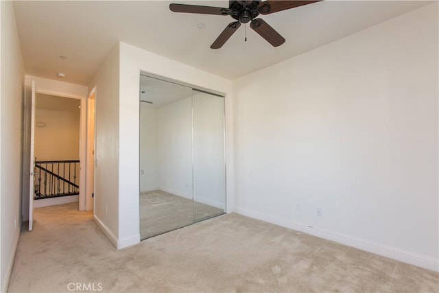 unfurnished bedroom featuring light colored carpet, ceiling fan, and a closet