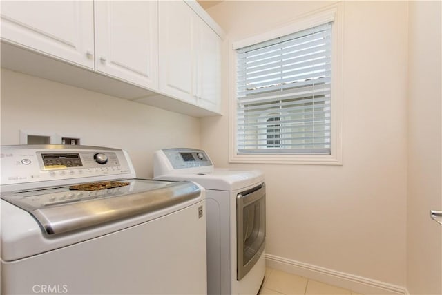 clothes washing area featuring light tile patterned floors, cabinets, and washing machine and clothes dryer