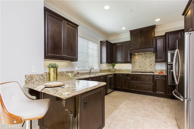 kitchen with sink, appliances with stainless steel finishes, ornamental molding, a kitchen bar, and kitchen peninsula