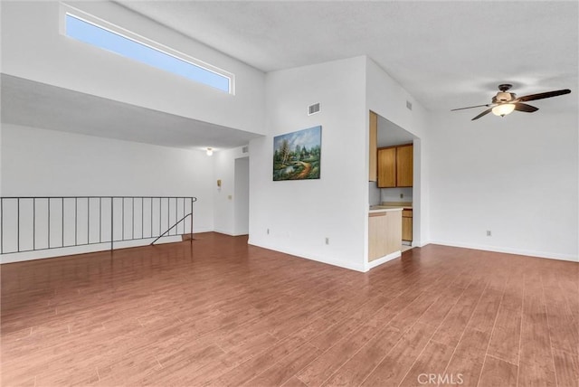 unfurnished living room featuring lofted ceiling, hardwood / wood-style floors, and ceiling fan