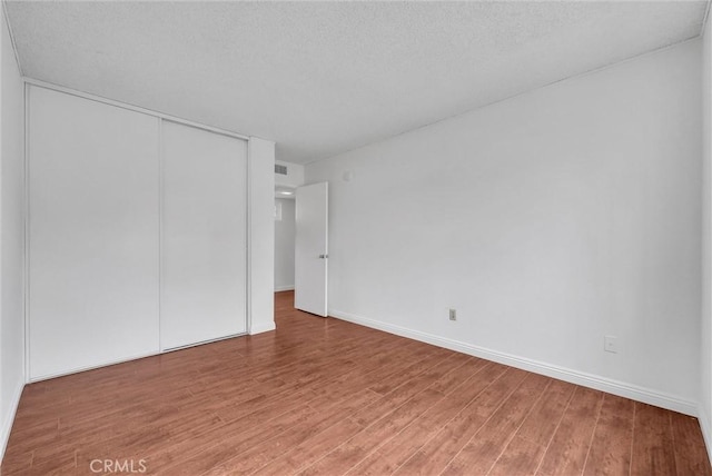 unfurnished bedroom featuring hardwood / wood-style flooring, a closet, and a textured ceiling