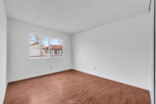 unfurnished room with wood-type flooring and a textured ceiling