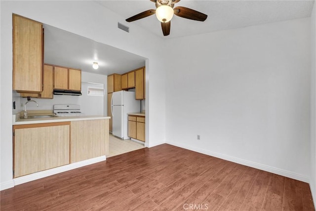 kitchen featuring light brown cabinetry, sink, white refrigerator, stove, and light wood-type flooring