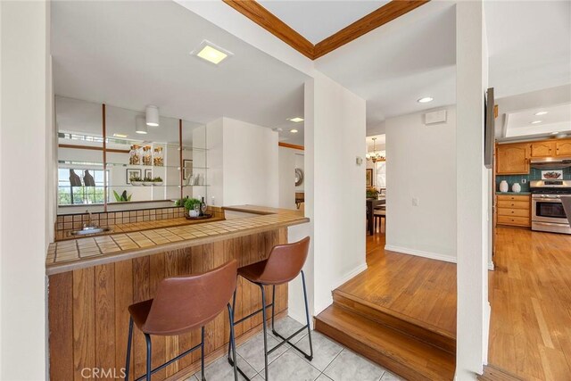 bar featuring tile counters, light hardwood / wood-style floors, and gas stove