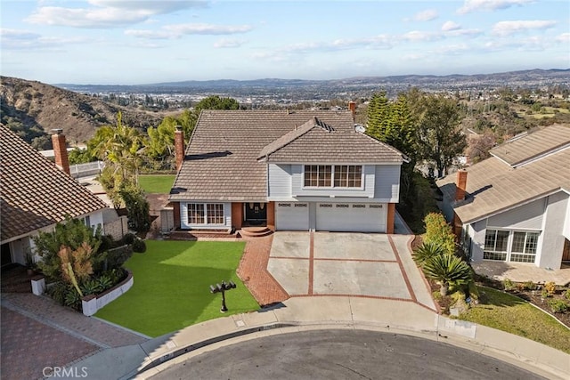 view of front facade with a garage, a mountain view, and a front lawn