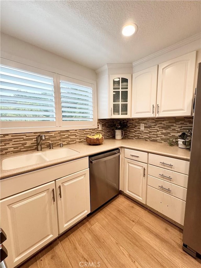 kitchen featuring sink, white cabinetry, stainless steel appliances, tasteful backsplash, and light hardwood / wood-style floors