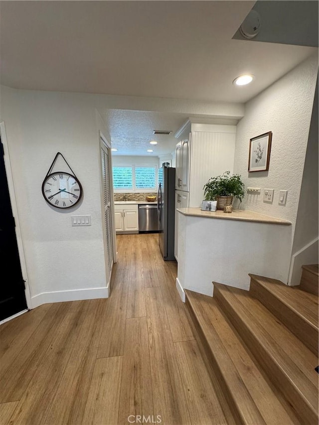 hallway featuring sink, a textured ceiling, and light wood-type flooring