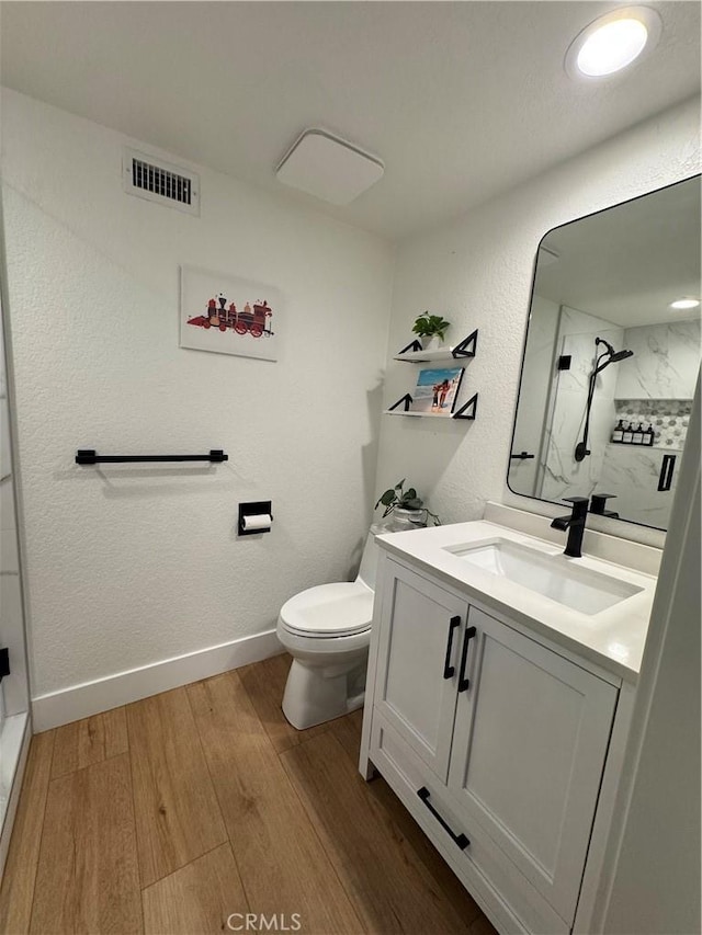 bathroom featuring hardwood / wood-style flooring, a shower, vanity, and toilet