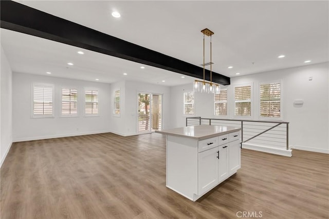 kitchen featuring a kitchen island, white cabinetry, hanging light fixtures, beam ceiling, and light wood-type flooring